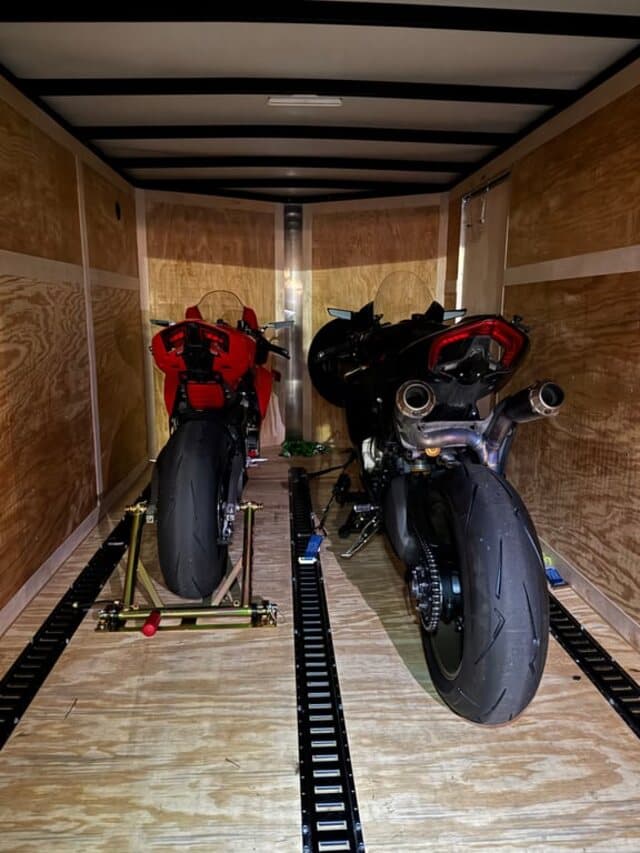 Two sport bikes on stands and strapped down inside an enclosed trailer