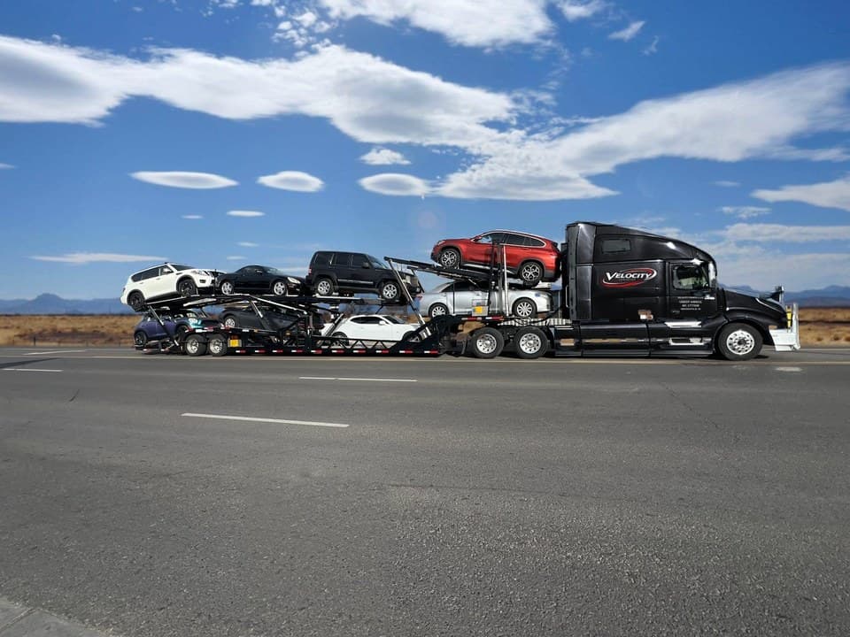 Velocity Logistics semi car hauler loaded on both decks, on a desert highway