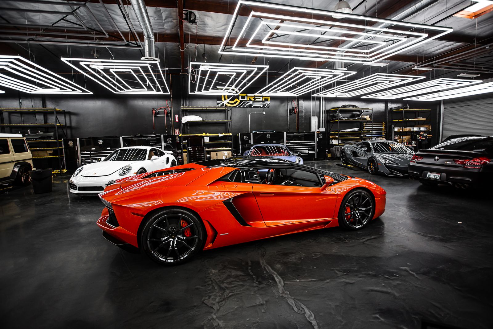 Exotic and luxury cars — including a Lamborghini and a Porsche — parked in a detailing garage